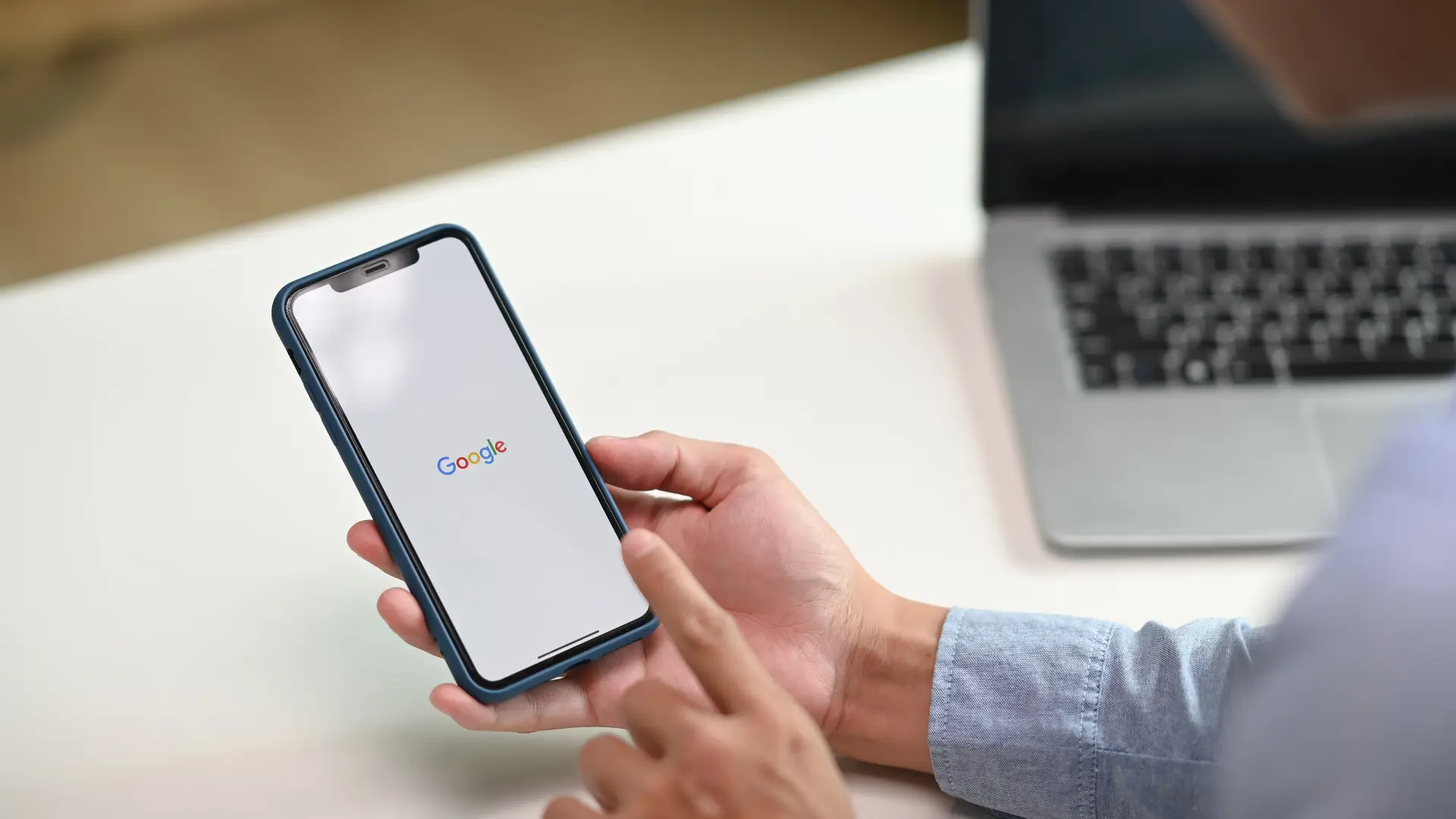 Un homme tenant un téléphone portable avec l'écran Google dessus